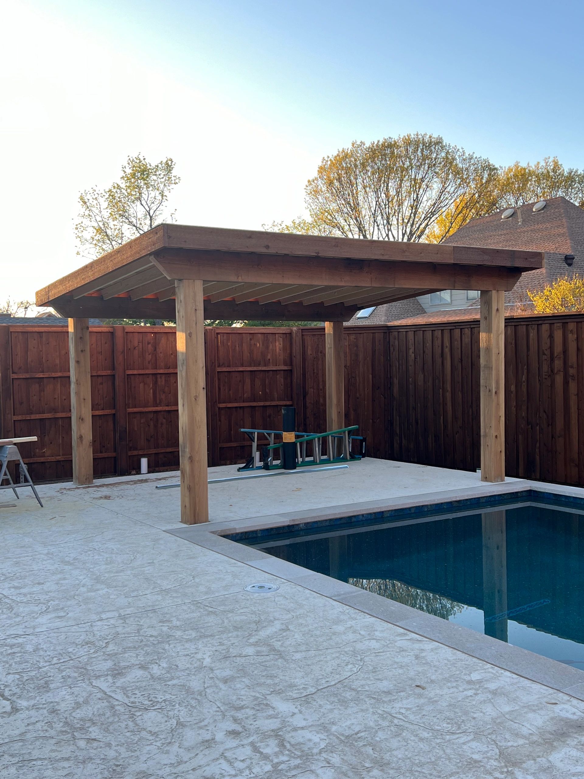 Outdoor wooden pavilion structure with backyard fencing