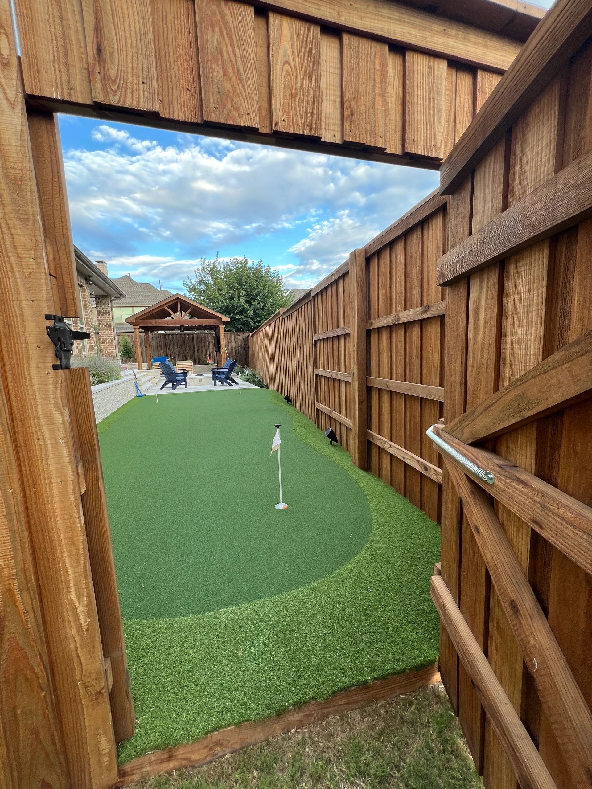 Residential backyard putting green with wooden gate